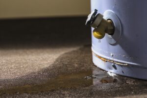Water leaking from the faucet on a residential electric water heater sitting on a concrete floor.